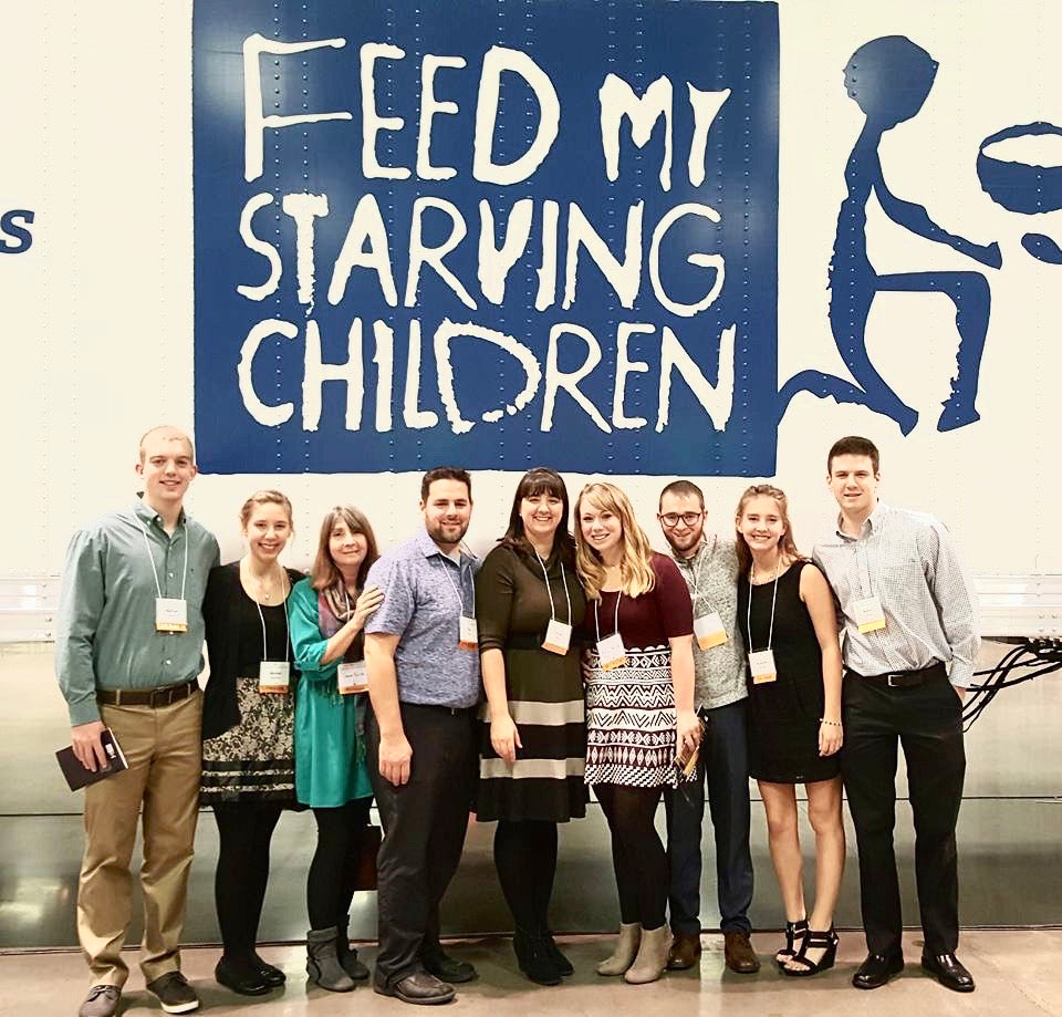 SnackBox employees standing in front of a Feed My Starving Children sign after volunteering