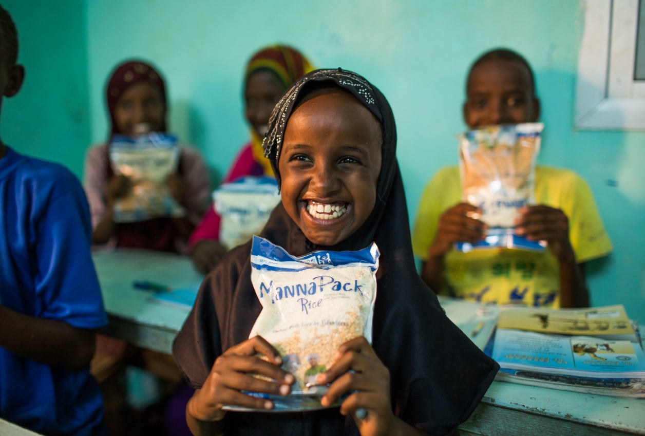 Feed my starving children rice manna packs child holding manna food pack with other children holding manna packs