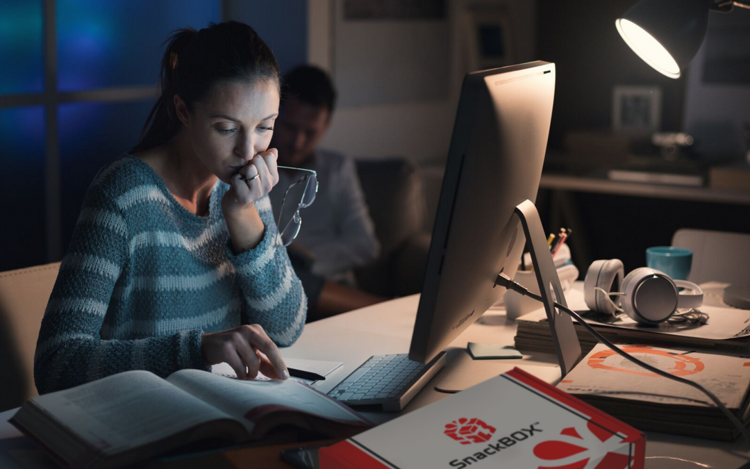 student studying for final exam with snackbox on desk