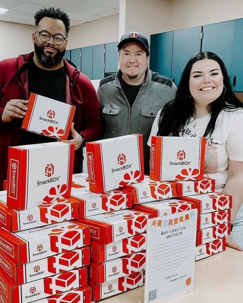 3 SnackBox wholesale warehouse packers, showing off their large stack of packed SnackBoxes, ready for shipment