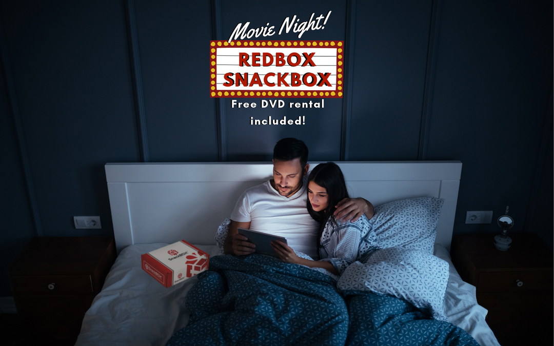 couple laying on bed watching a show on ipad with snack box on bed